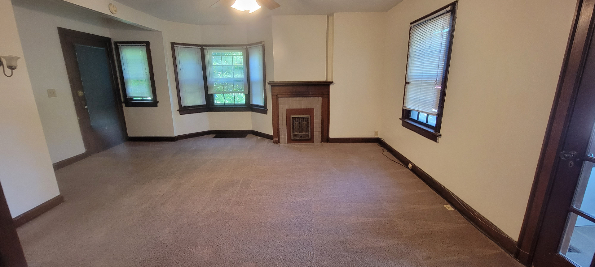 2054 Iuka Ave. A living room with original tile fireplace, wood mantel, and bay window