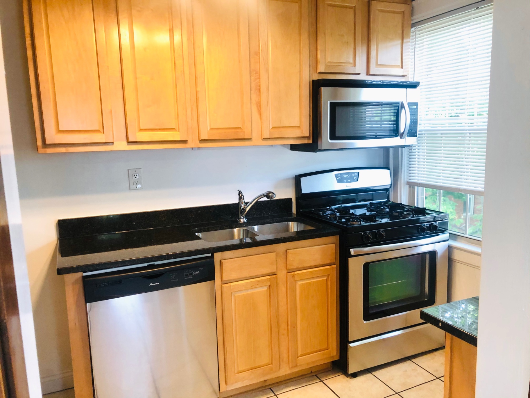 Unit L kitchen with stainless steel gas range, microwave, granite counters, and dishwasher