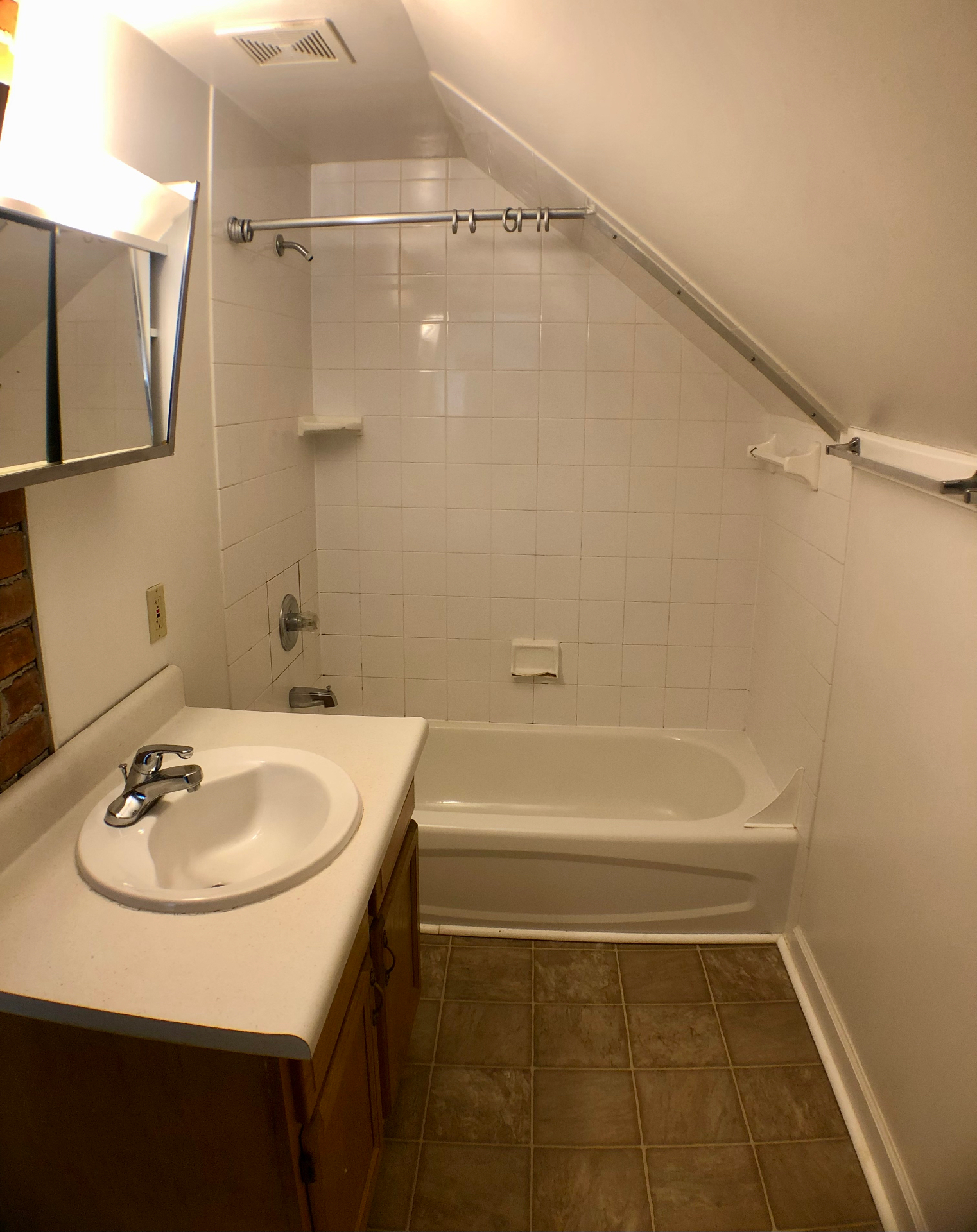 Bathroom with full tub, white tile surround, and sharply sloped ceiling