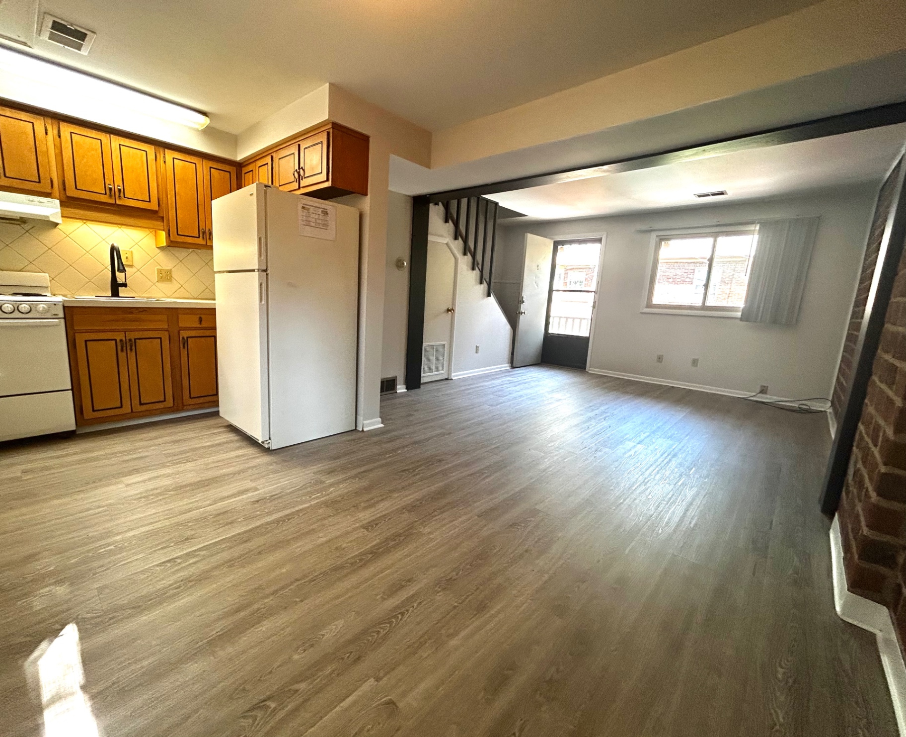 2011 Summit St. Unit E open concept kitchen and living area with wood cabinets and plank flooring