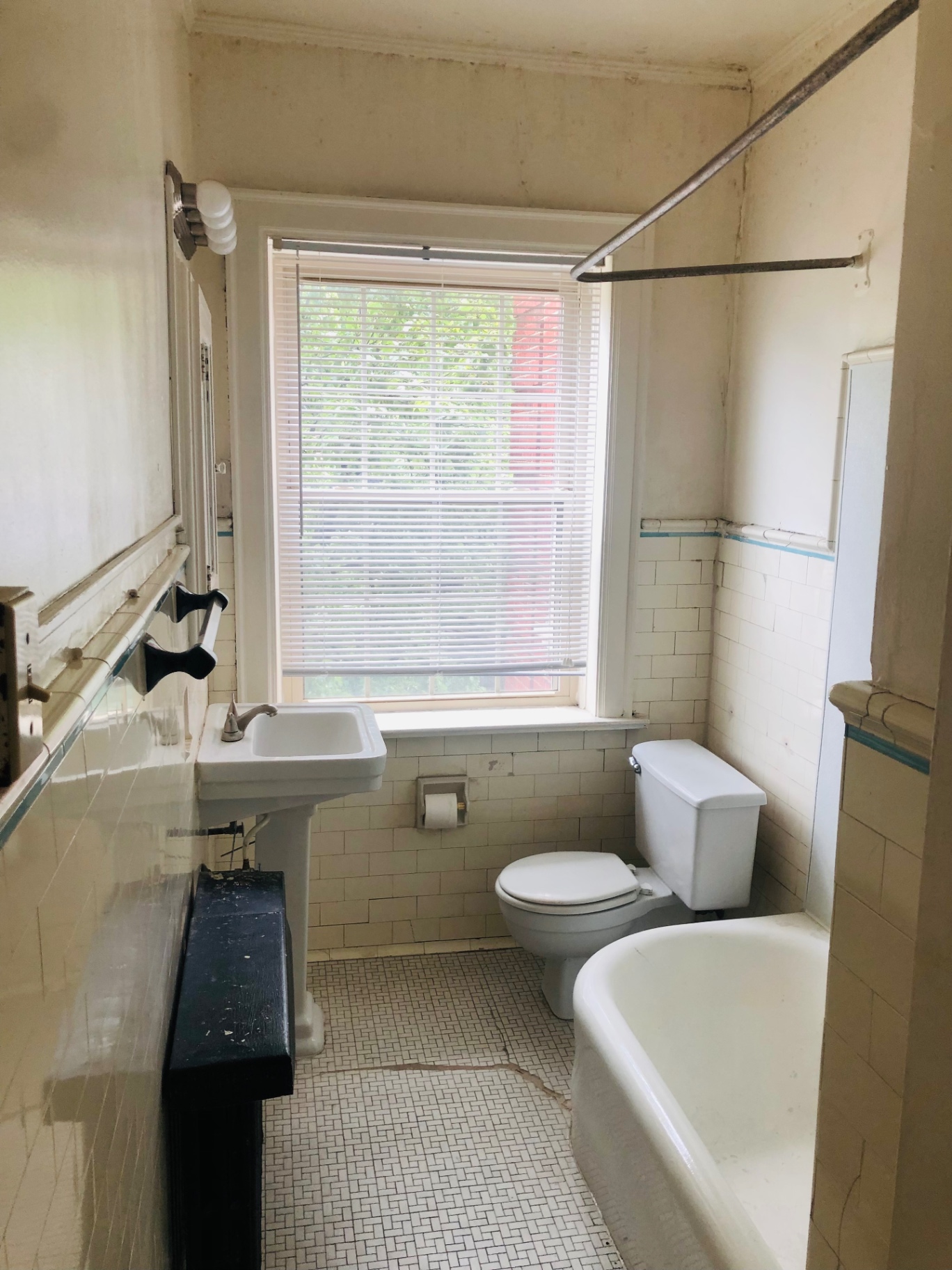 Unit F bathroom with subway tile, clawfoot tub, pedestal sink, and window