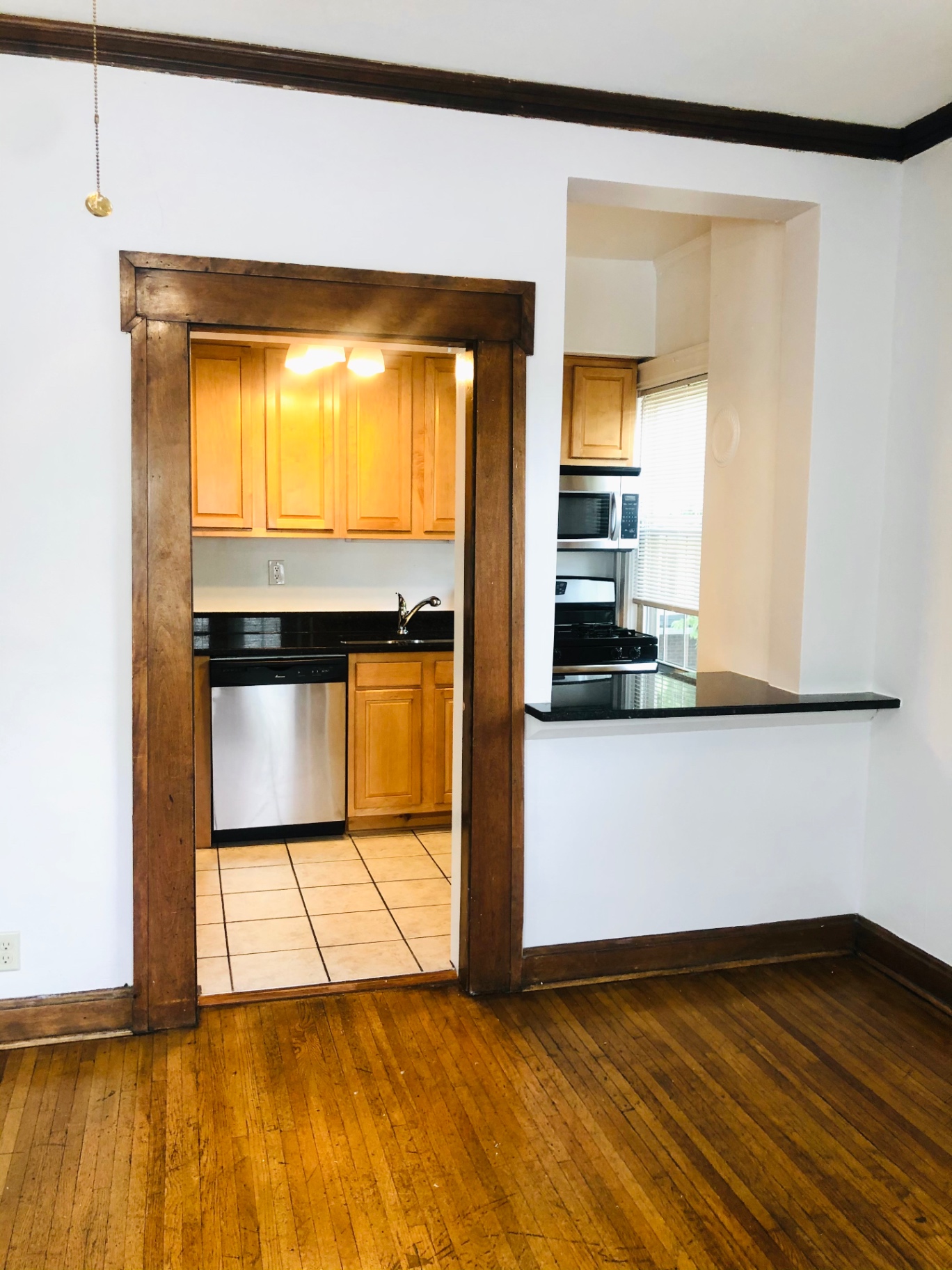 Unit L dining view into kitchen with maple cabinets and granite pass-through counter