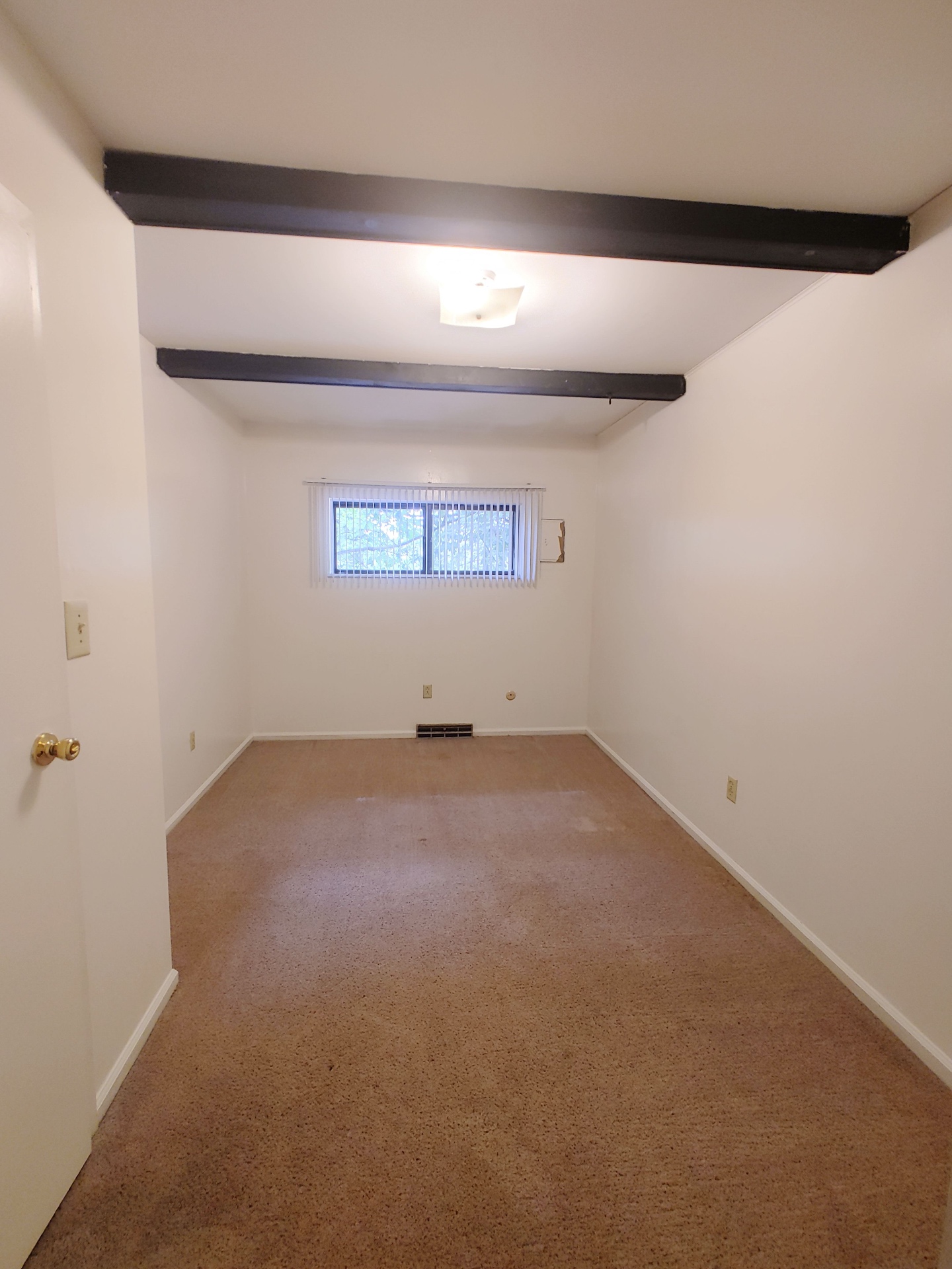 2016 Iuka Ave. bedroom with exposed ceiling beams, fresh carpet, and low window