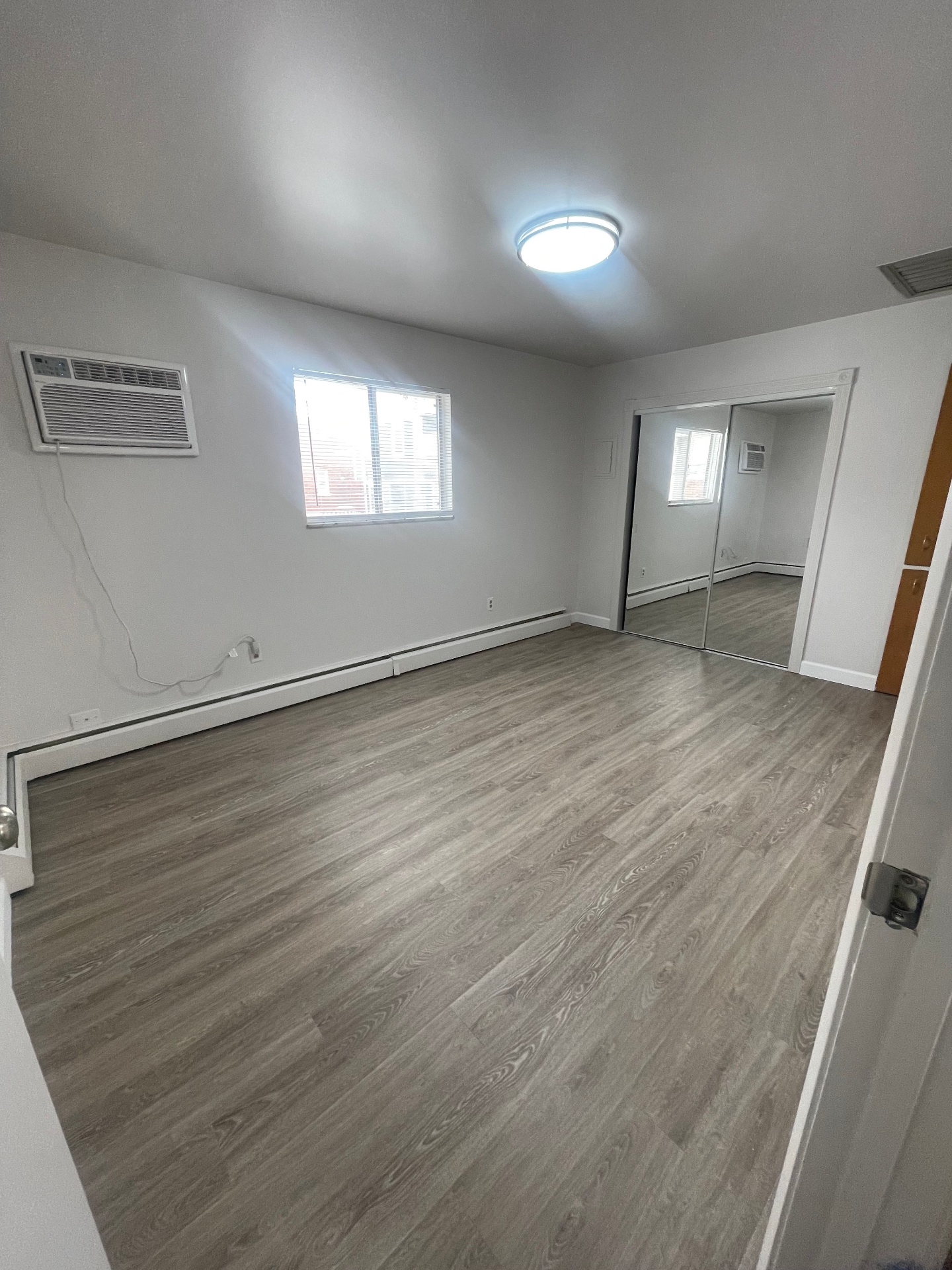 1827 N 4th St. Unit 8 second bedroom with bright window, wall AC, and mirrored closet