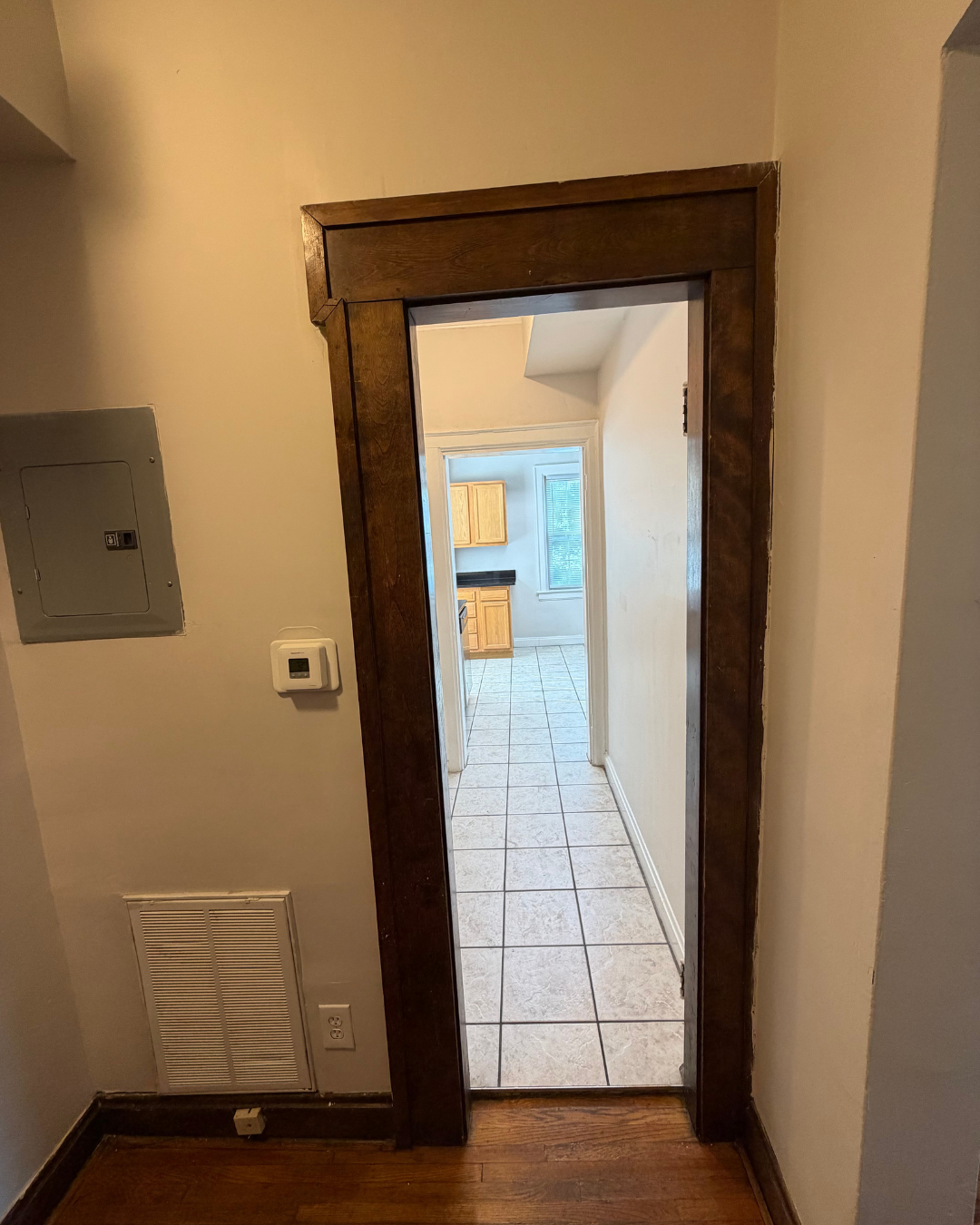 Utility hallway with electrical panel leading to the kitchen