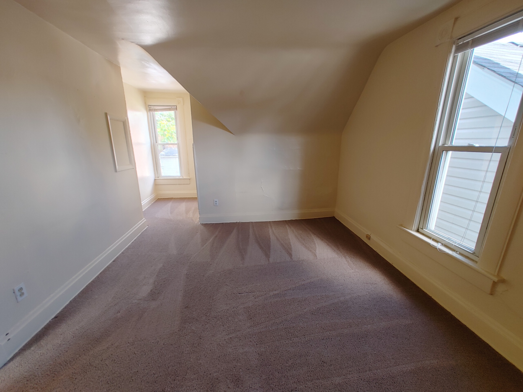 Rear unit upstairs bedroom nook with dormer walls and two windows