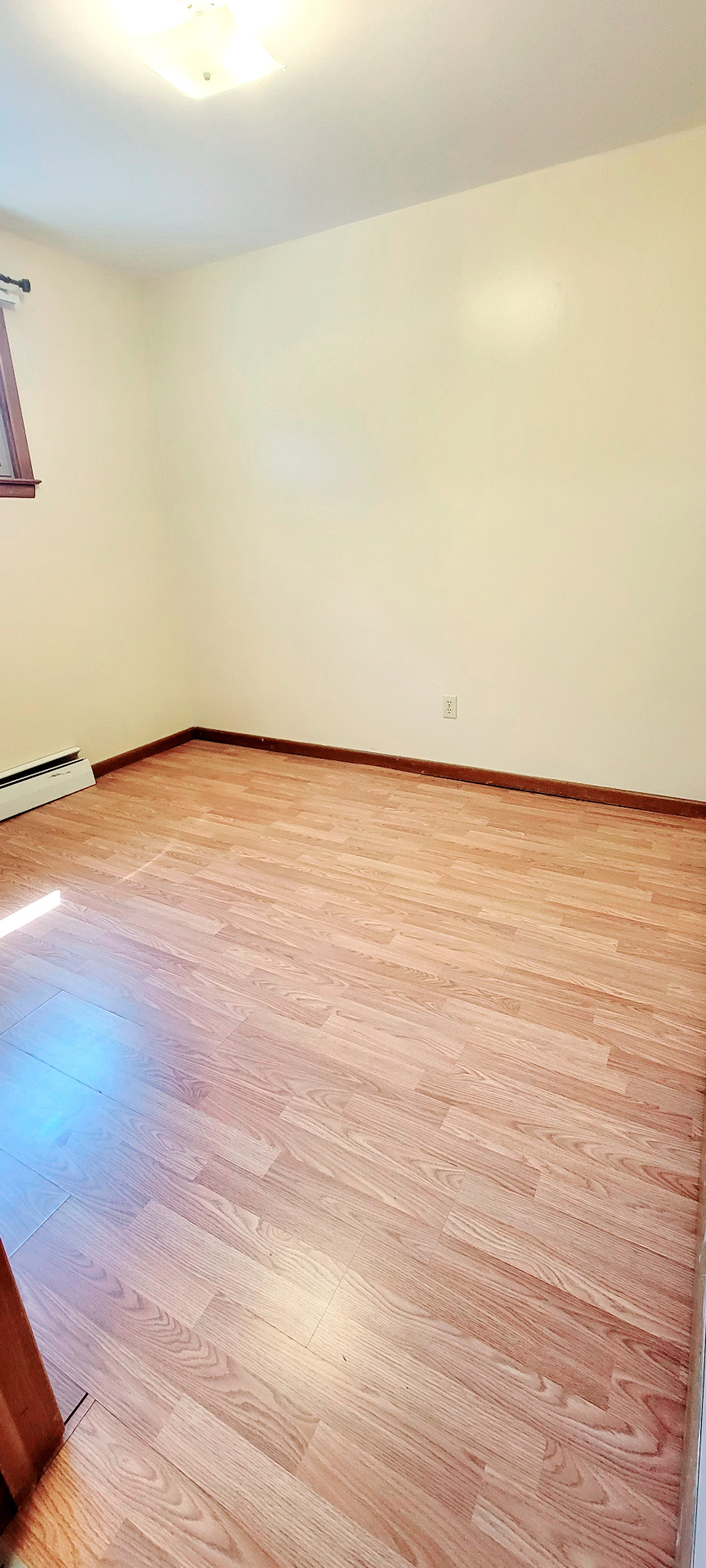 2040 Iuka Ave. 3A bright bedroom with laminate floors, window light, and baseboard heat