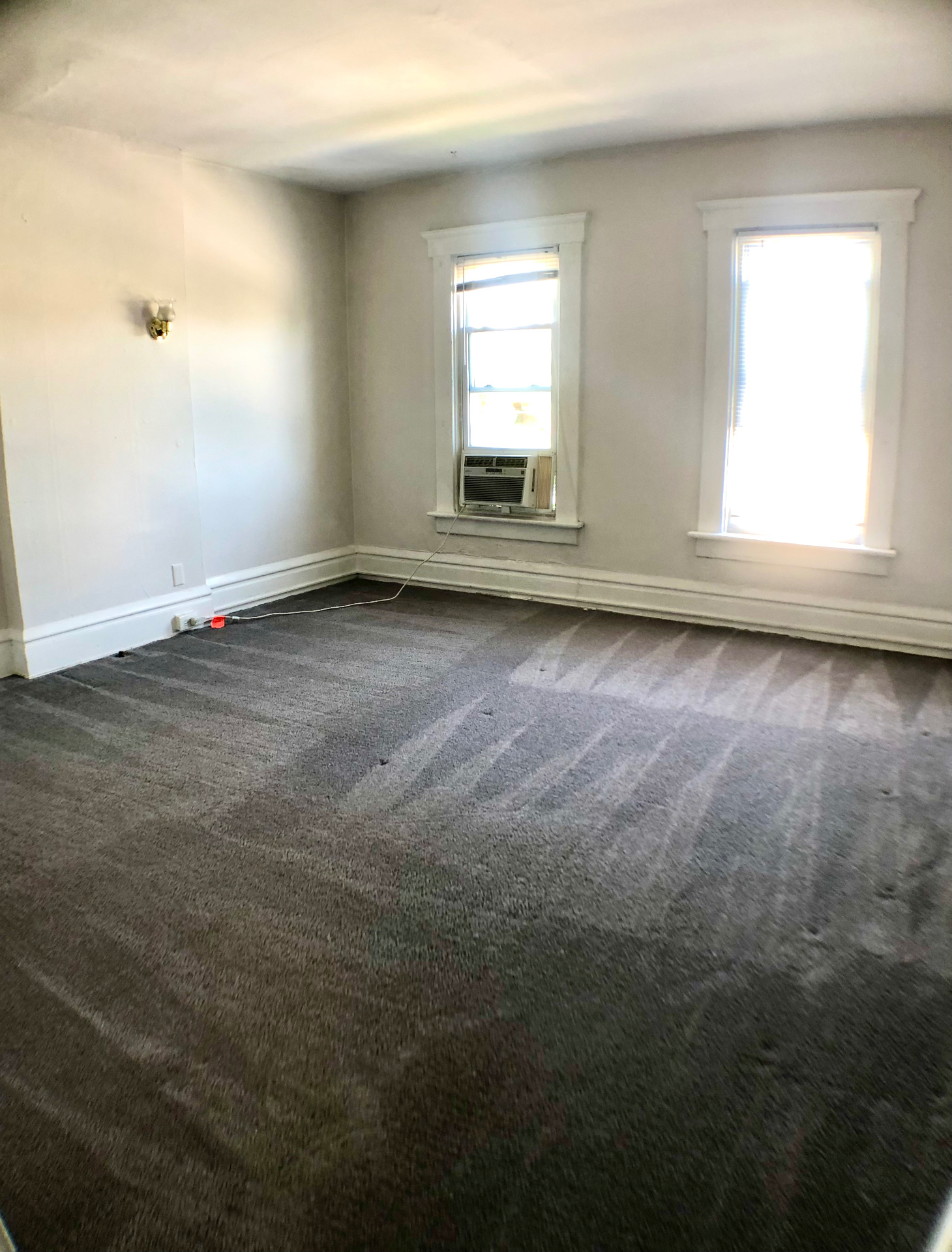 117 W 9th bedroom with grey carpet, wall sconce and dual windows