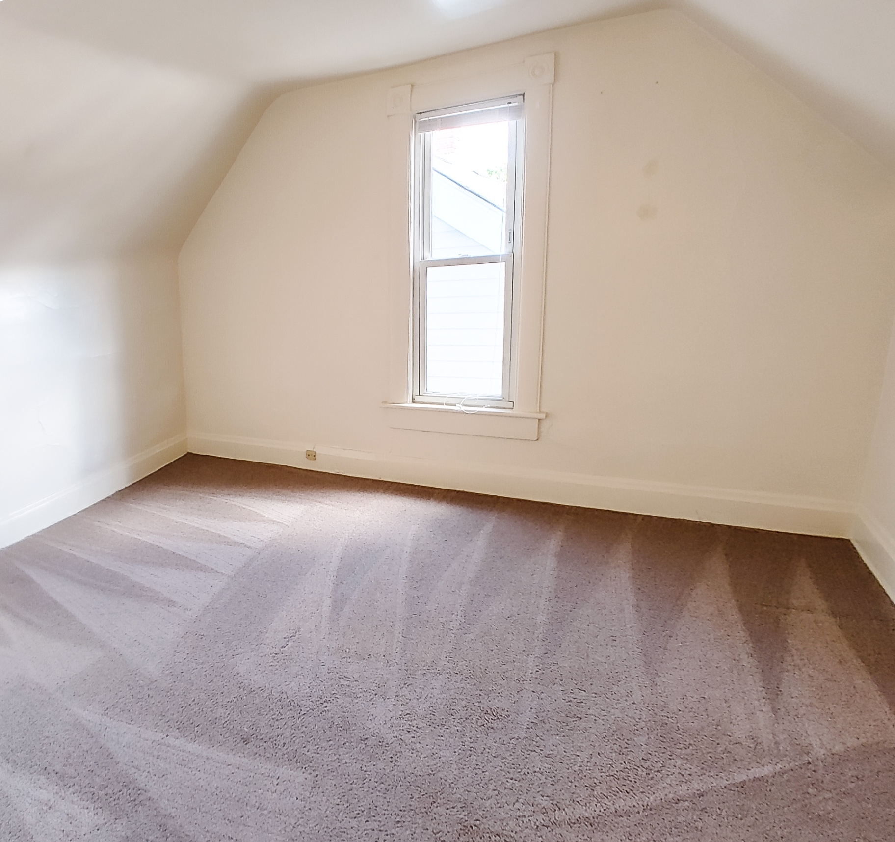 Rear unit upstairs bedroom with vaulted ceiling and tall window