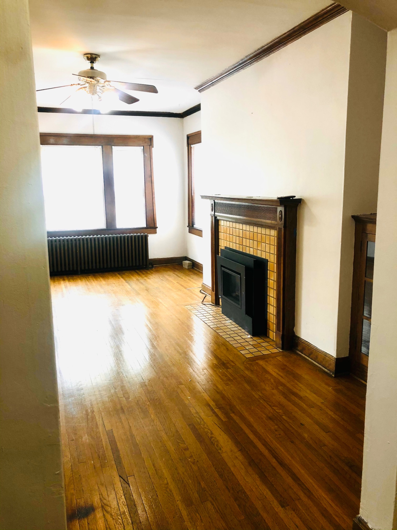 Unit L living room with tiled gas fireplace, hardwood floors, and sunlit windows