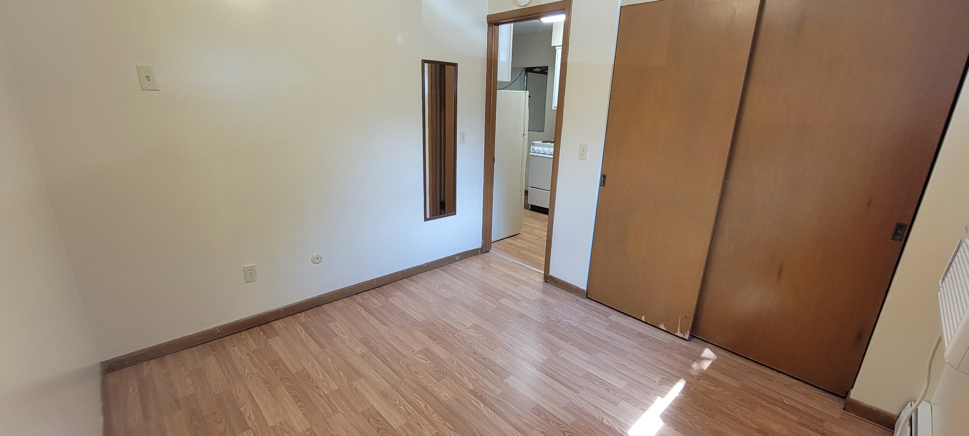 2040 Iuka Ave. 3A bedroom with laminate floors, sliding closet doors, and wall mirror
