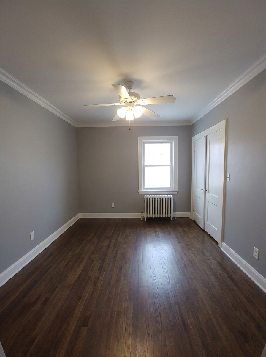 Unit C bedroom with gray walls, hardwood floors, and radiator