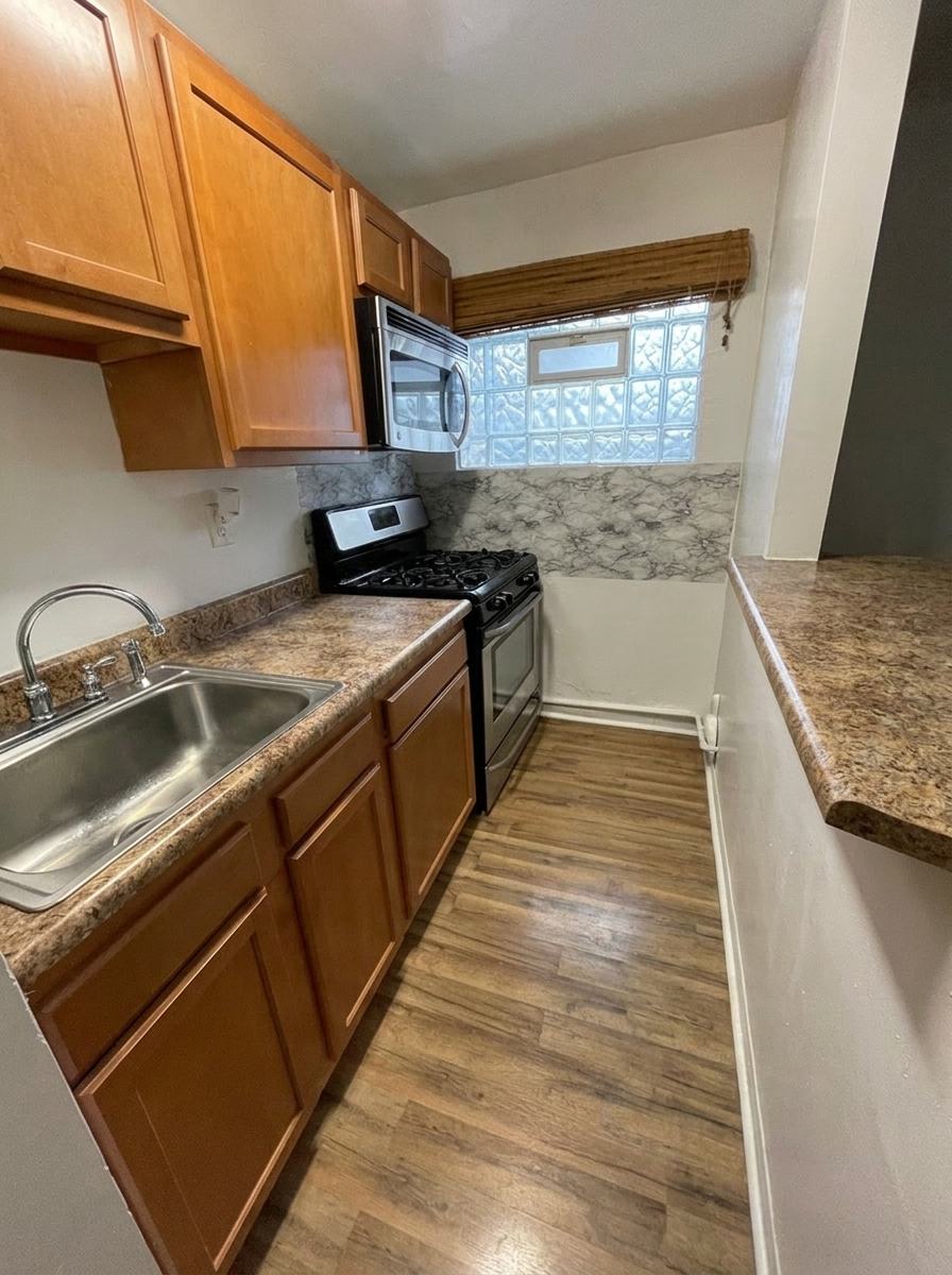 Unit M galley kitchen with gas range, microwave, and marble backsplash
