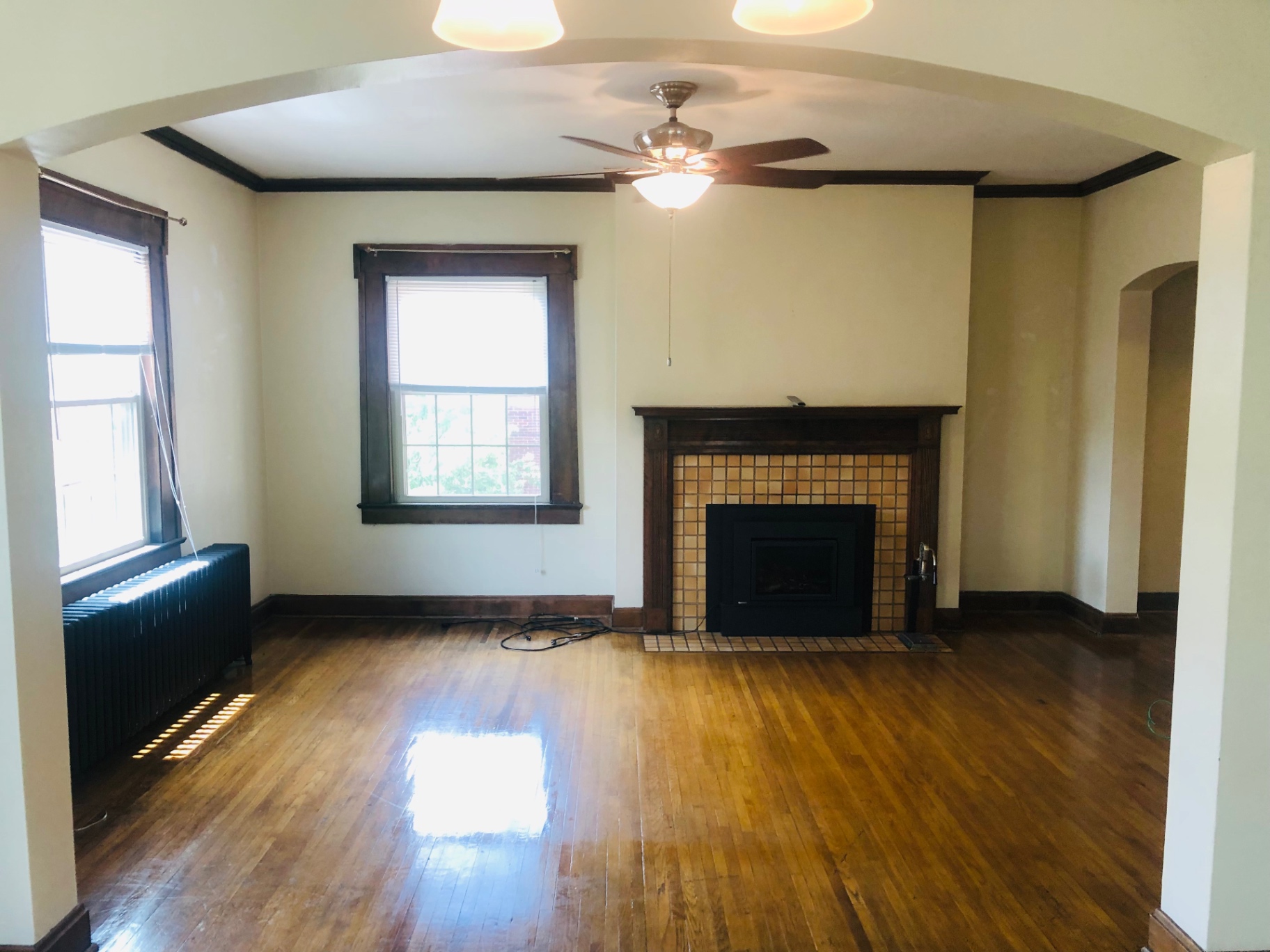 Unit K living room with tiled gas fireplace, hardwood floors, and arched entryway