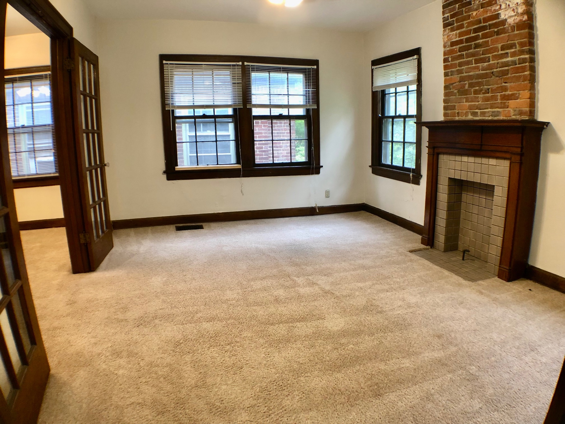 2054 Iuka Ave. D wide living room with original French doors, tile fireplace with exposed brick, and abundant natural light