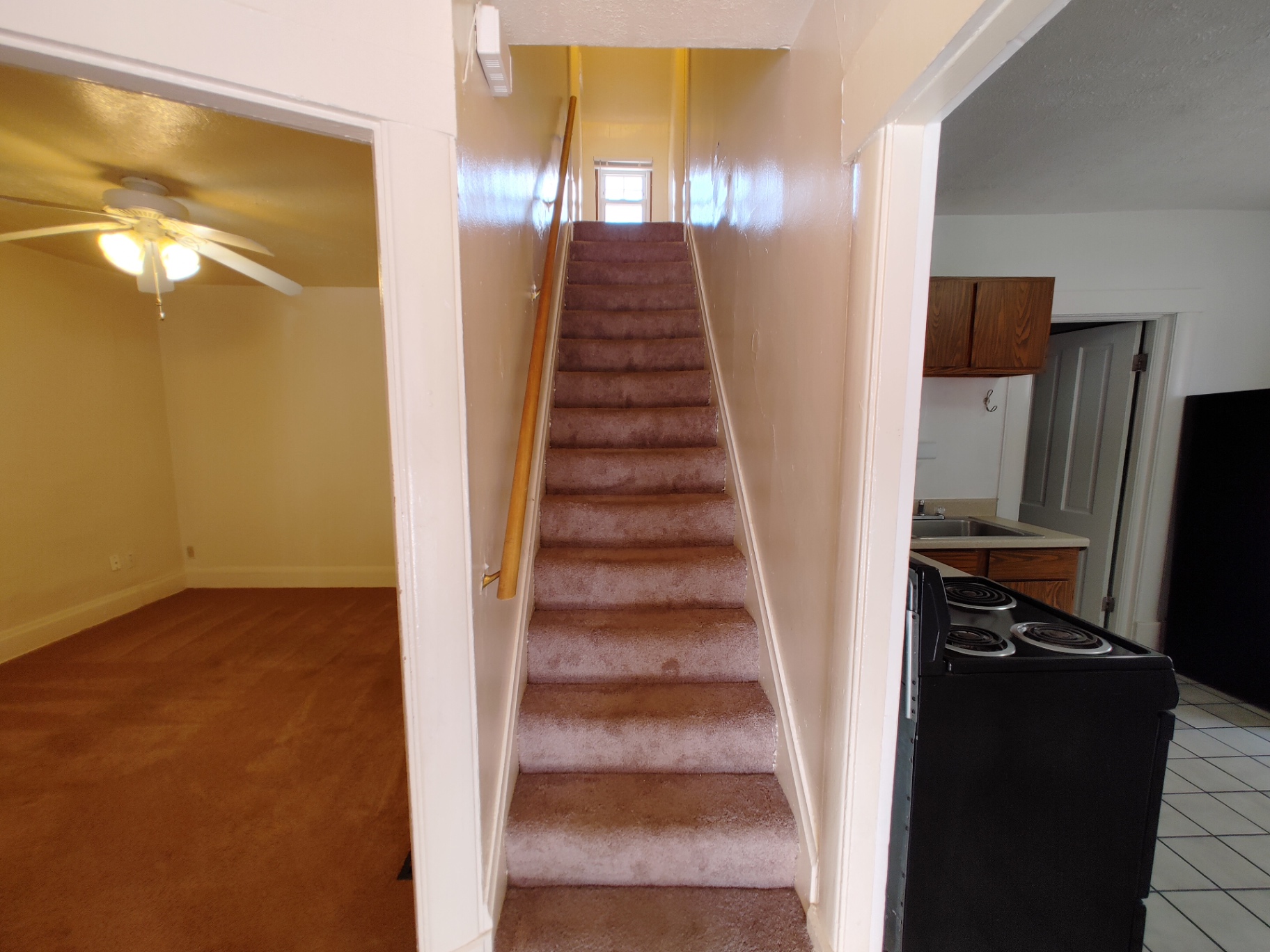 Rear unit foyer with carpeted staircase leading to upstairs bedrooms