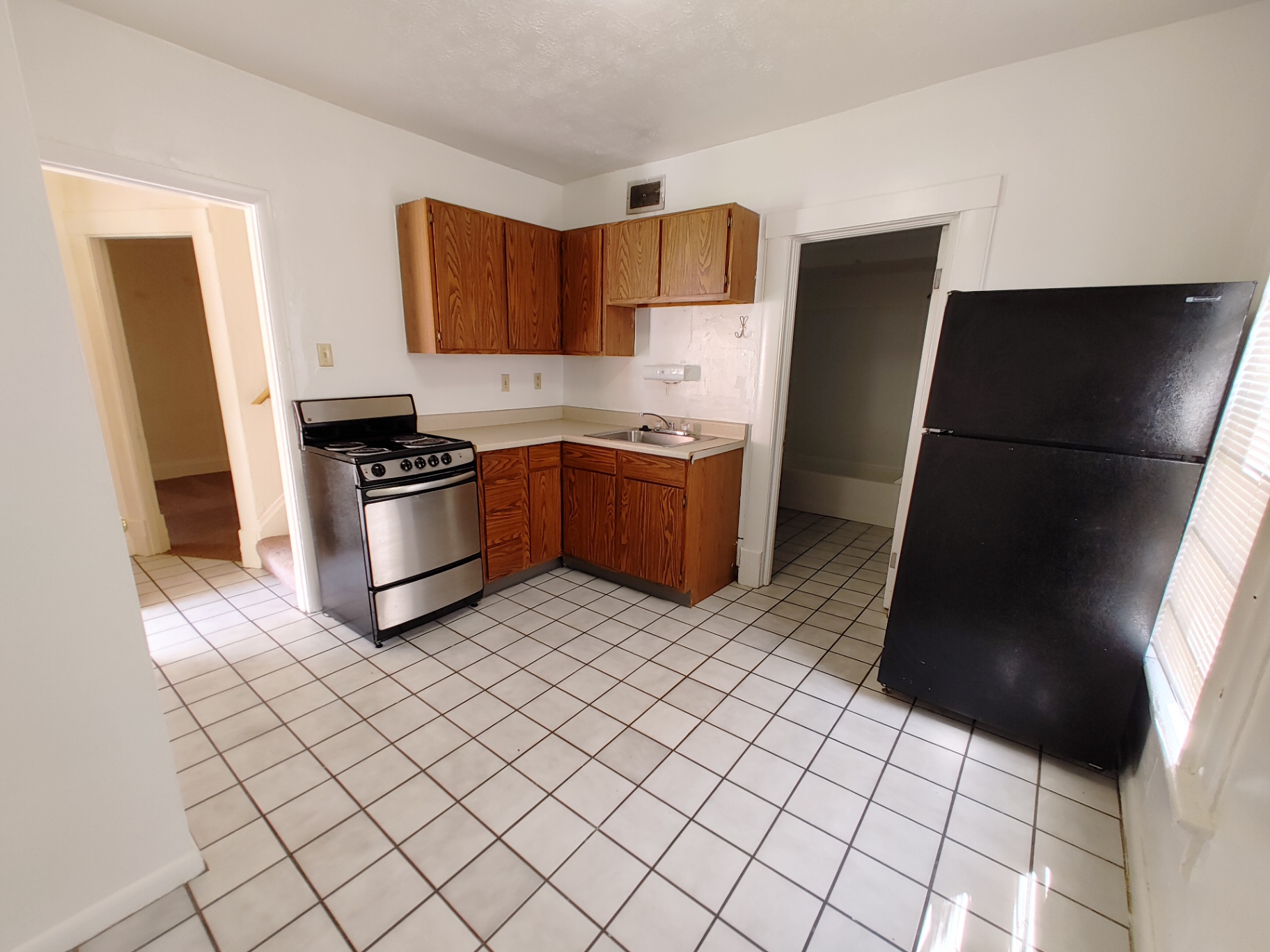 Rear unit bright eat-in kitchen with tile floor, stainless-front range, full-size fridge and updated cabinets