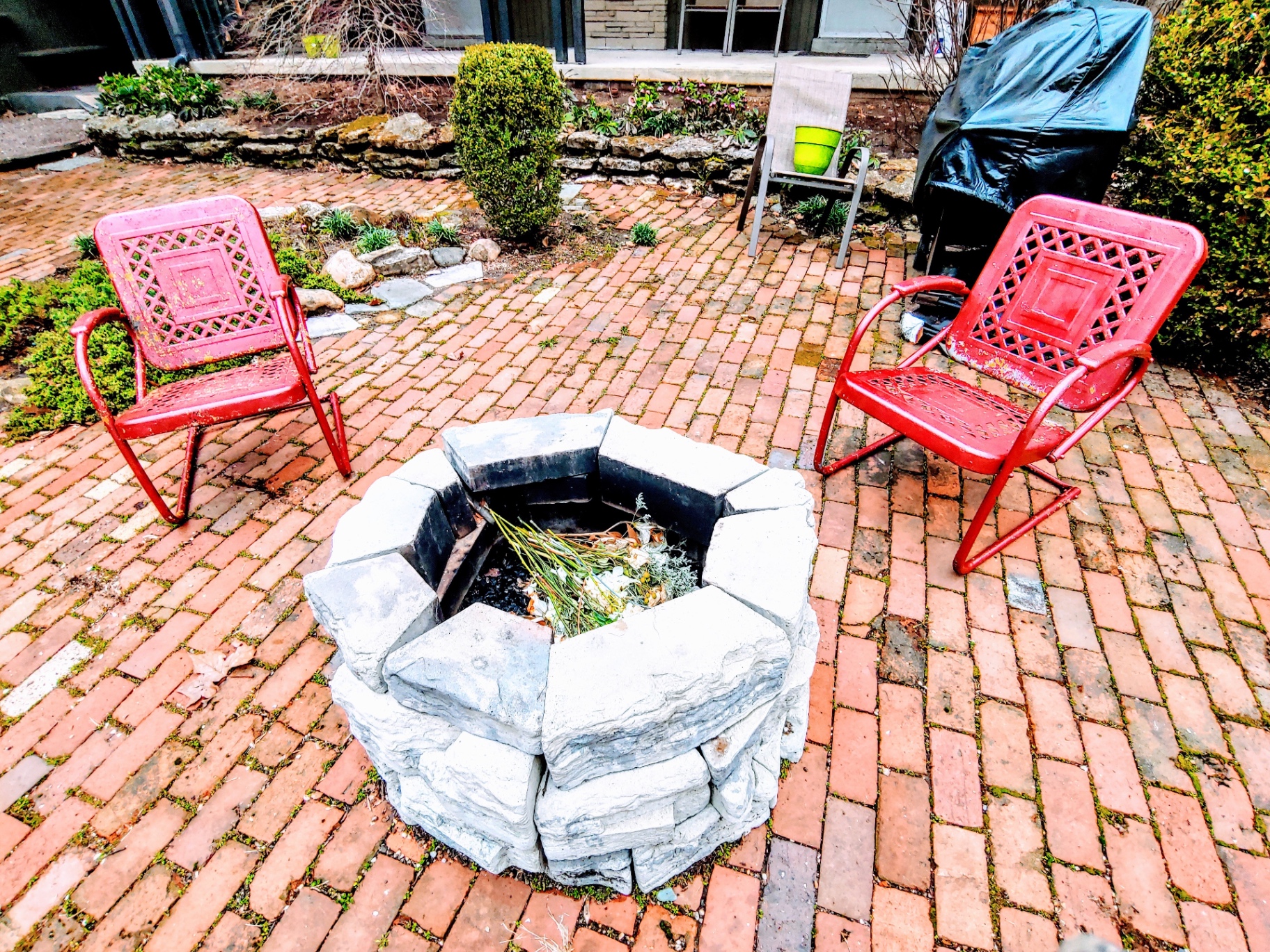 2040 Iuka Ave. 1B stone fire pit with vintage red patio chairs on brick patio