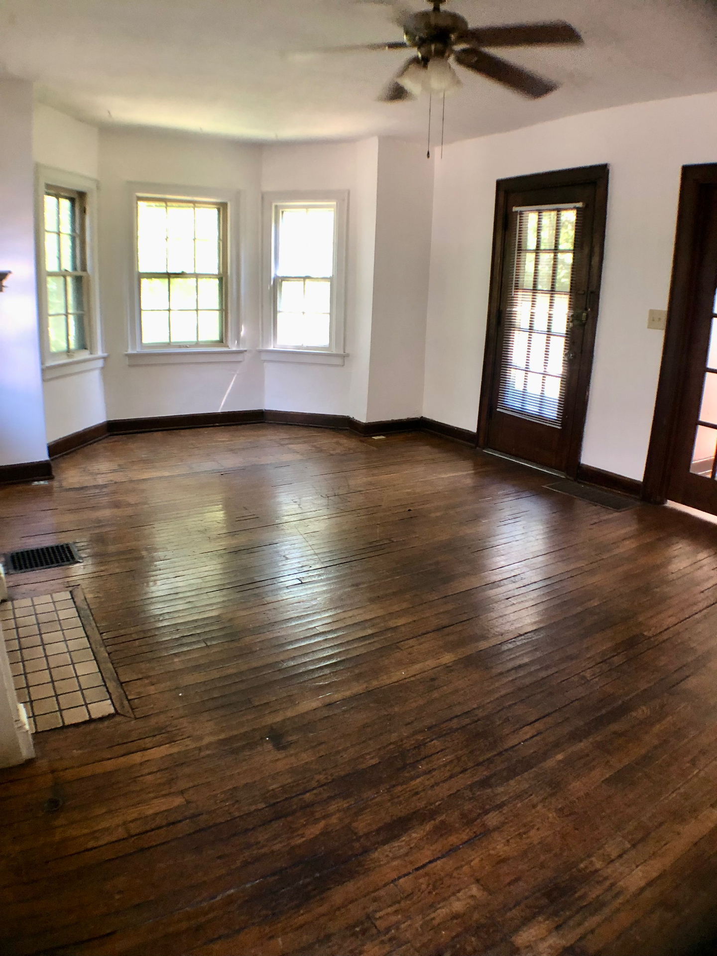2044 Iuka Ave. A sunlit living room with original hardwood floors, bay windows, and French-door entry