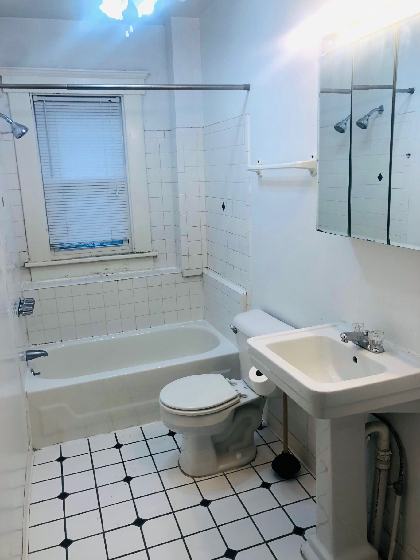119 W 9th bathroom with pedestal sink, tiled tub surround and classic tile floor