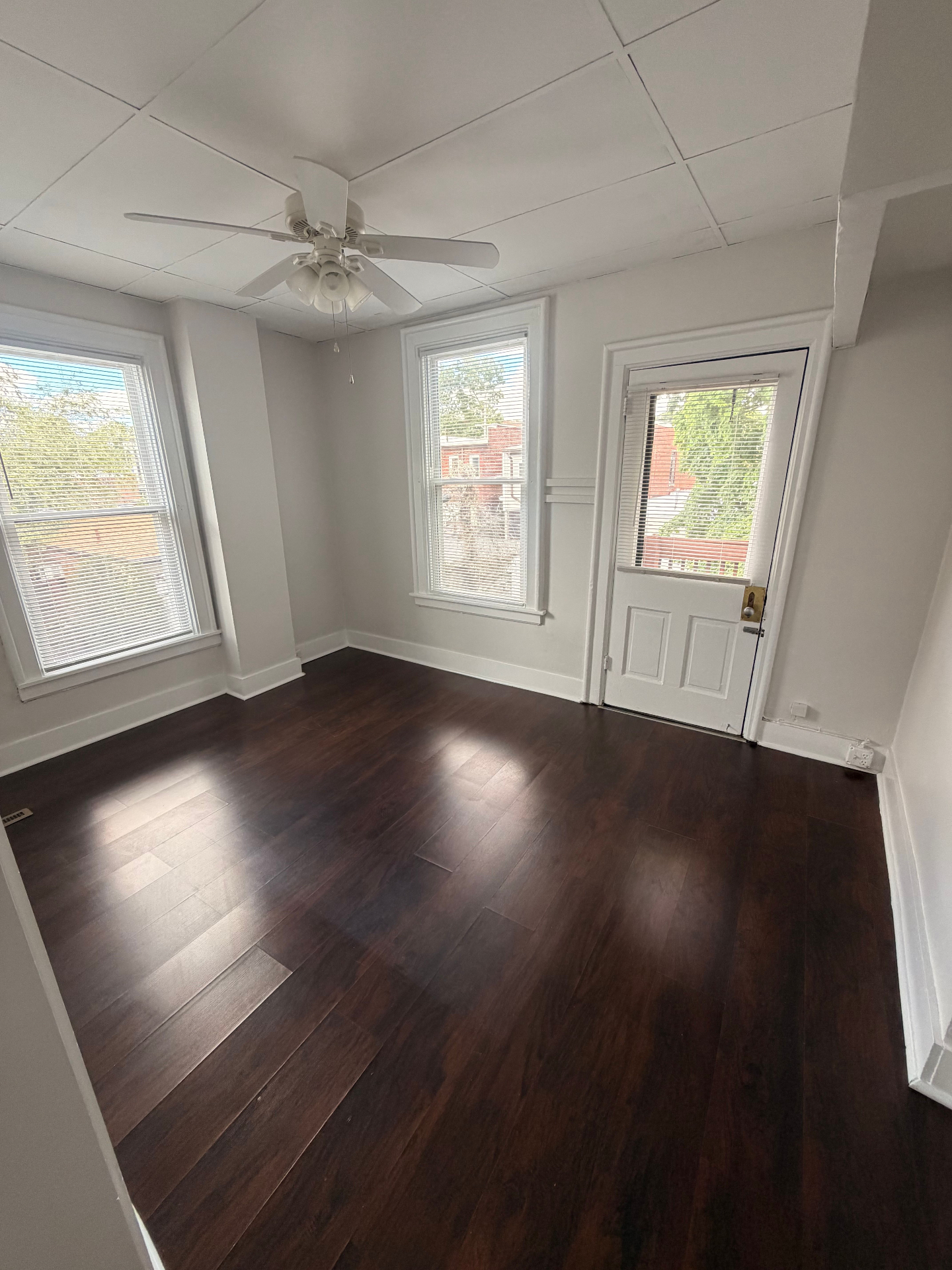 3340 Chestnut Upstairs bright living room with dark floors, three windows and a back door to the deck