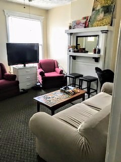 115 W 9th living room with fireplace mantel, TV and comfortable seating