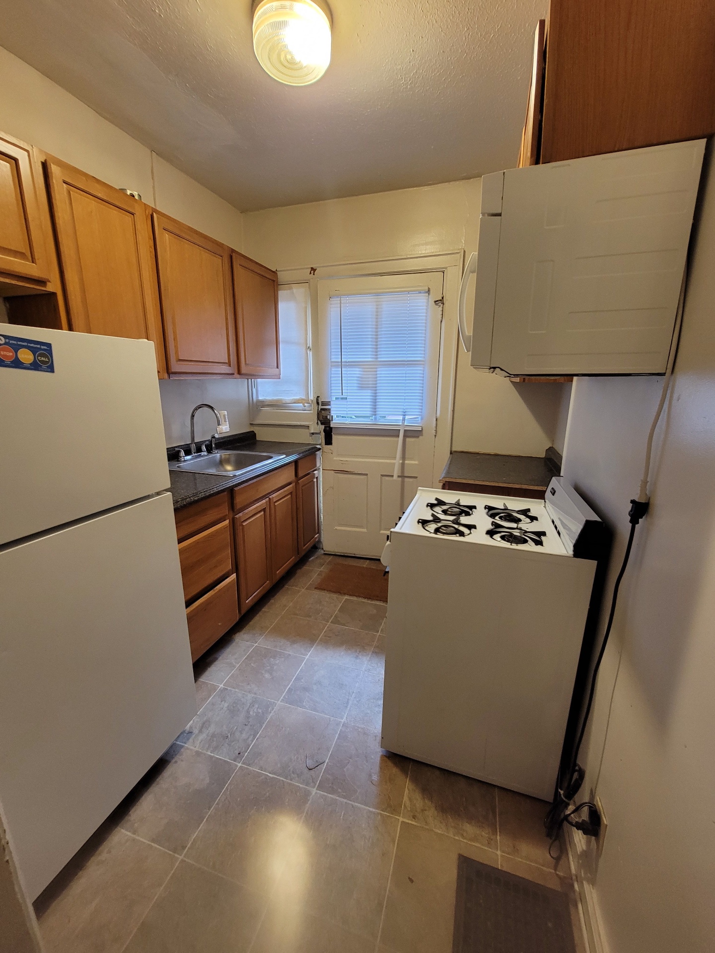 2048 Iuka Ave. B galley kitchen with gas range, full-size fridge, and rear door to exterior stairs