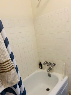 2026 Summit St. white-tile tub/shower with striped shower curtain