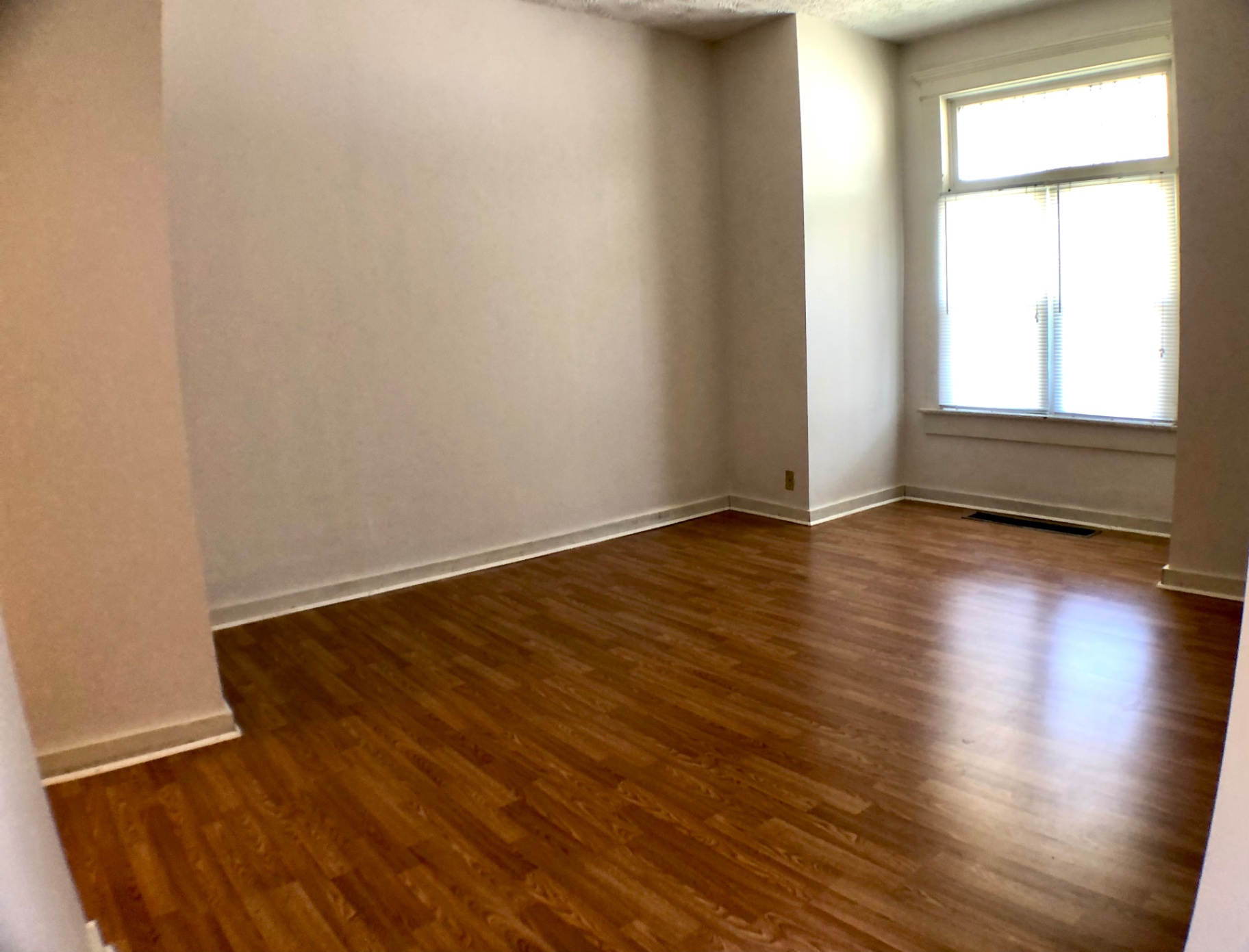 Unit A living room with hardwood floors, bright corner window and neutral walls