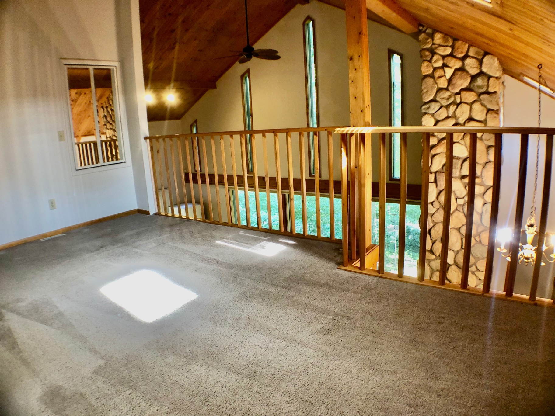 2040 Iuka Ave House upstairs loft with tall windows, stone chimney, and vaulted wood ceiling