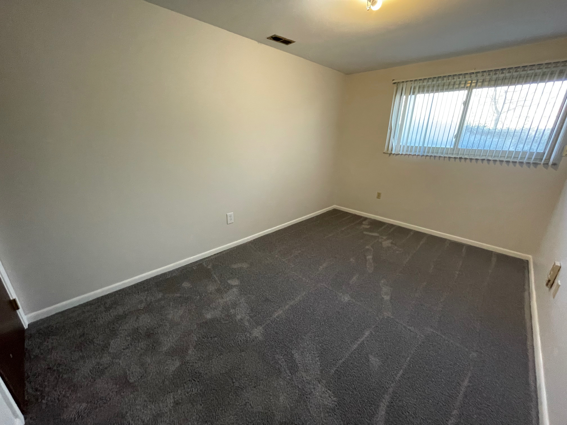2020 Summit St. freshly carpeted bedroom with neutral walls and wide window blinds