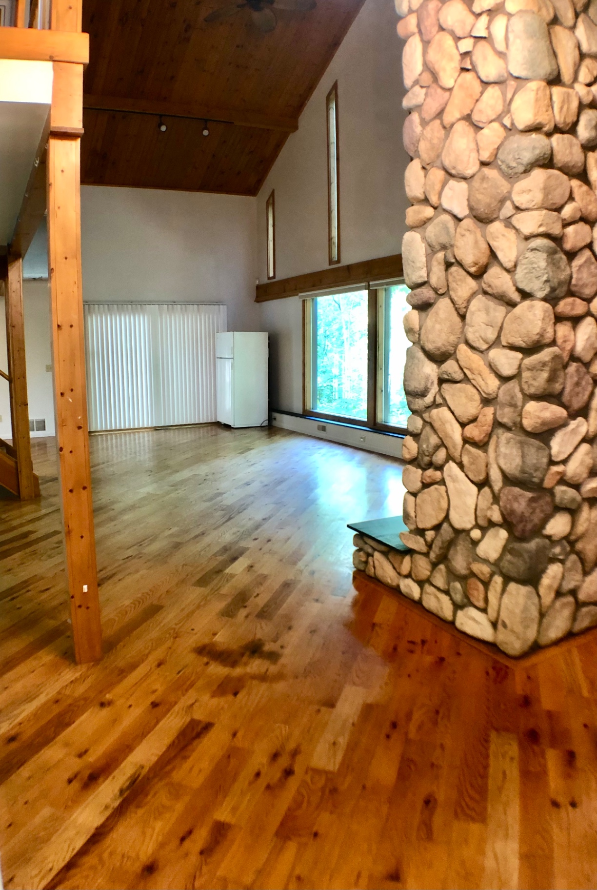 2040 Iuka Ave House great room with soaring vaulted ceiling, river-stone fireplace, and hardwood floors