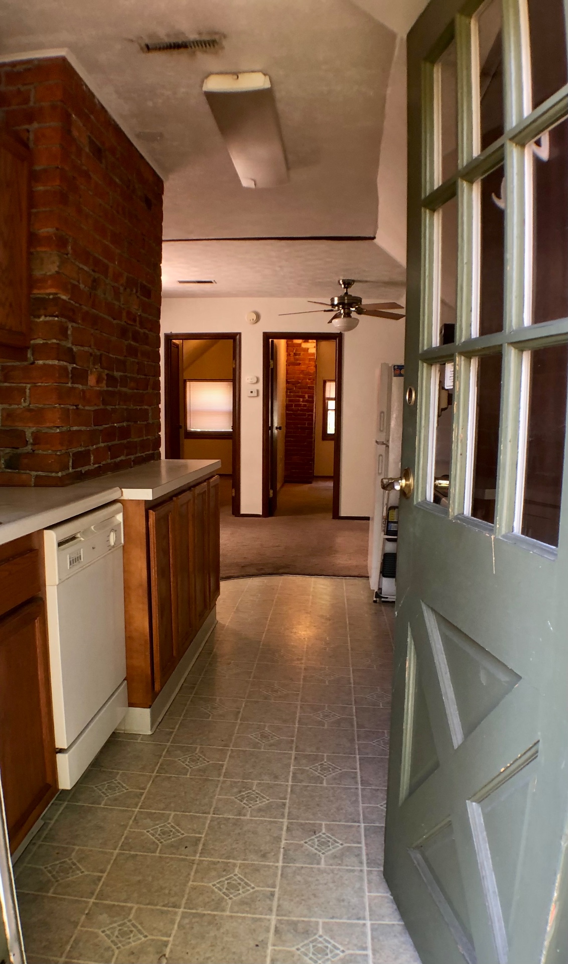Entry doorway view into kitchen with brick chimney and living room beyond