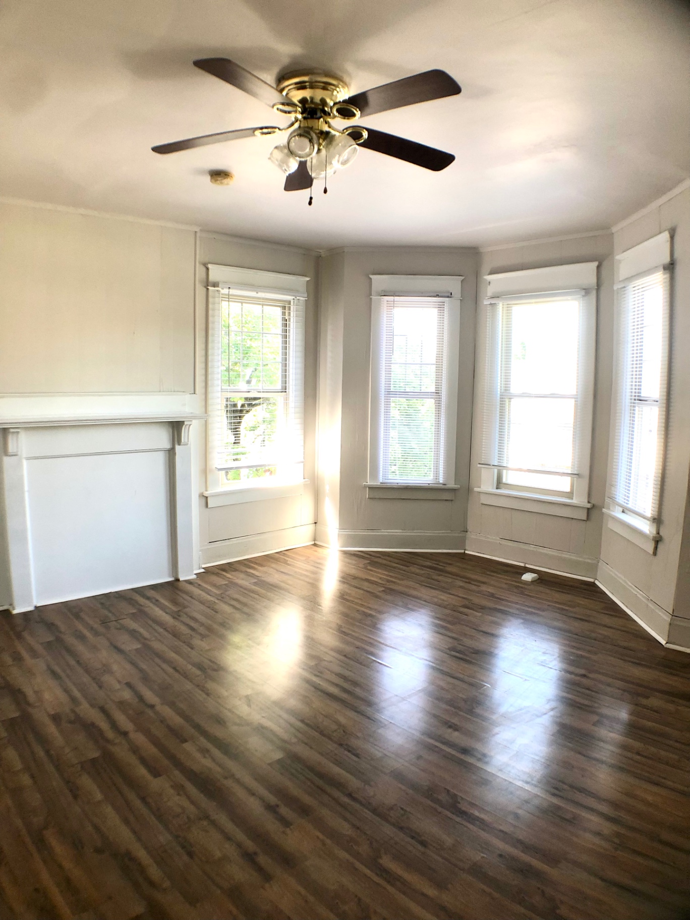 1814 Summit St. living room with white mantel, ceiling fan, and multi-window bay