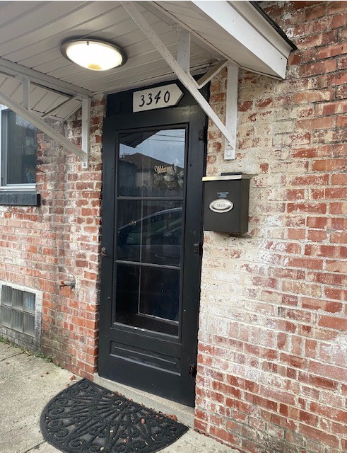 3338 Chestnut private downstairs entry with black storm door and brick surround
