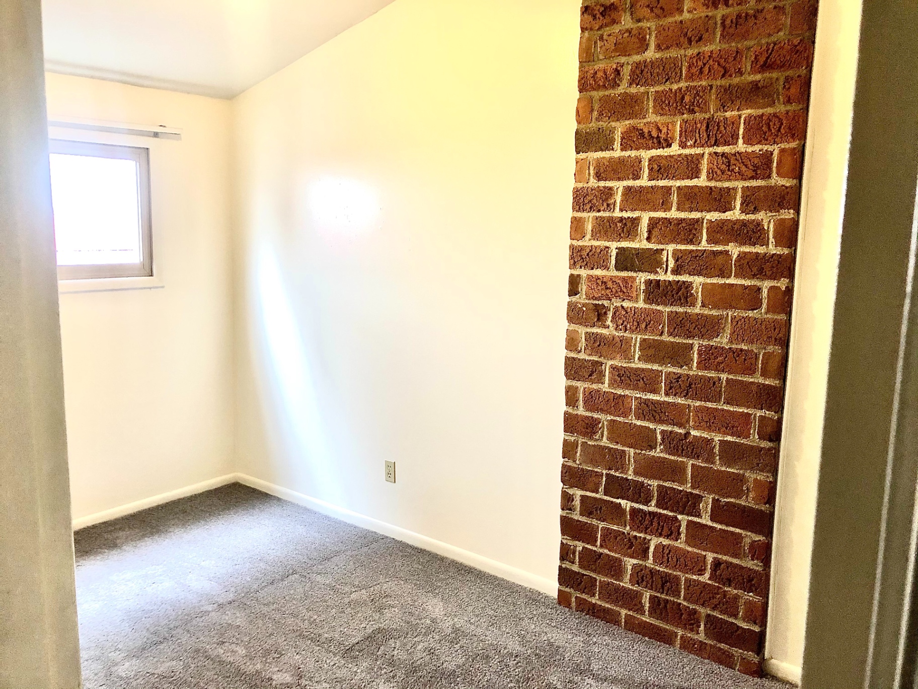 2011 Summit St. Unit B carpeted bedroom with exposed brick accent wall
