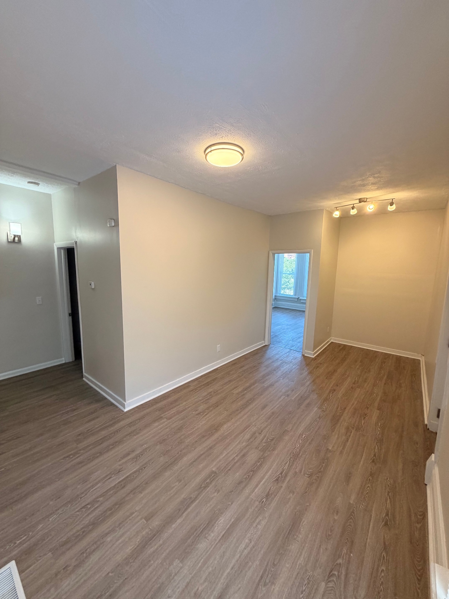 133½ open living area looking toward the bedroom with updated flooring and neutral walls