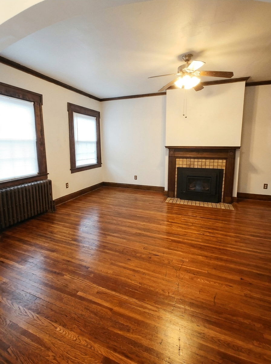 Unit C living room with gas insert fireplace, hardwood floors, and radiator