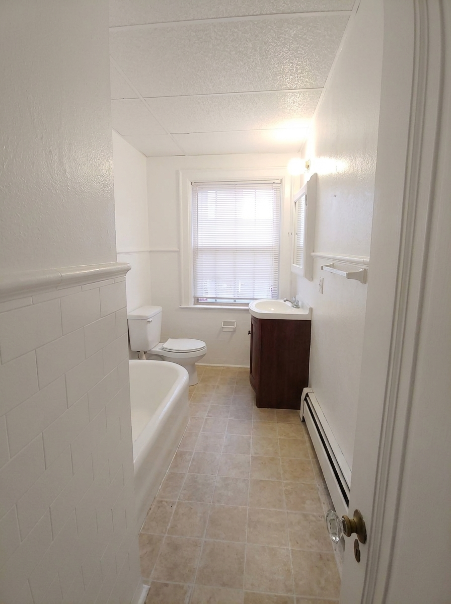 Unit C bathroom with tub, vanity, and window