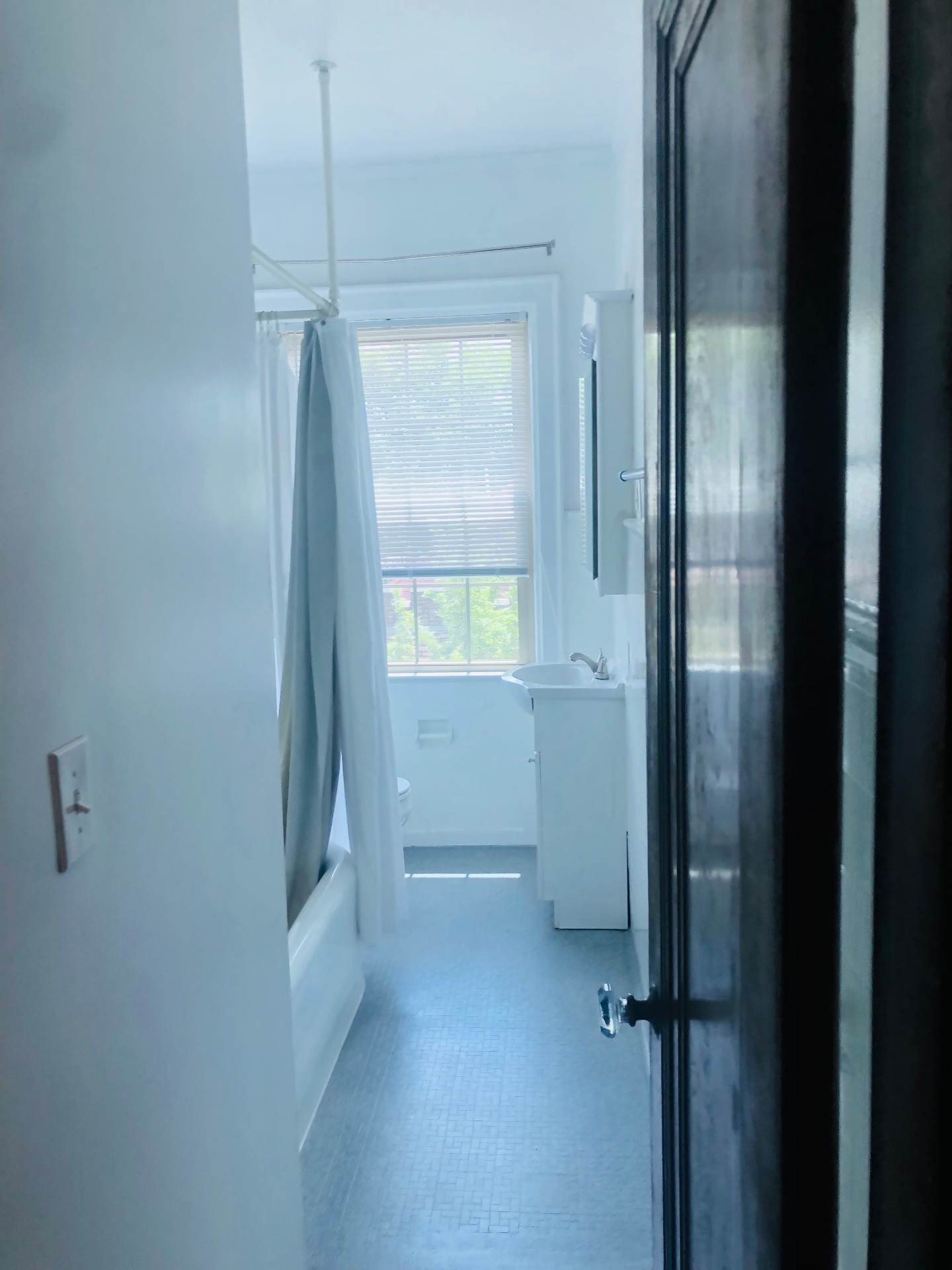 Unit K bathroom view with tub, shower curtain, and vanity