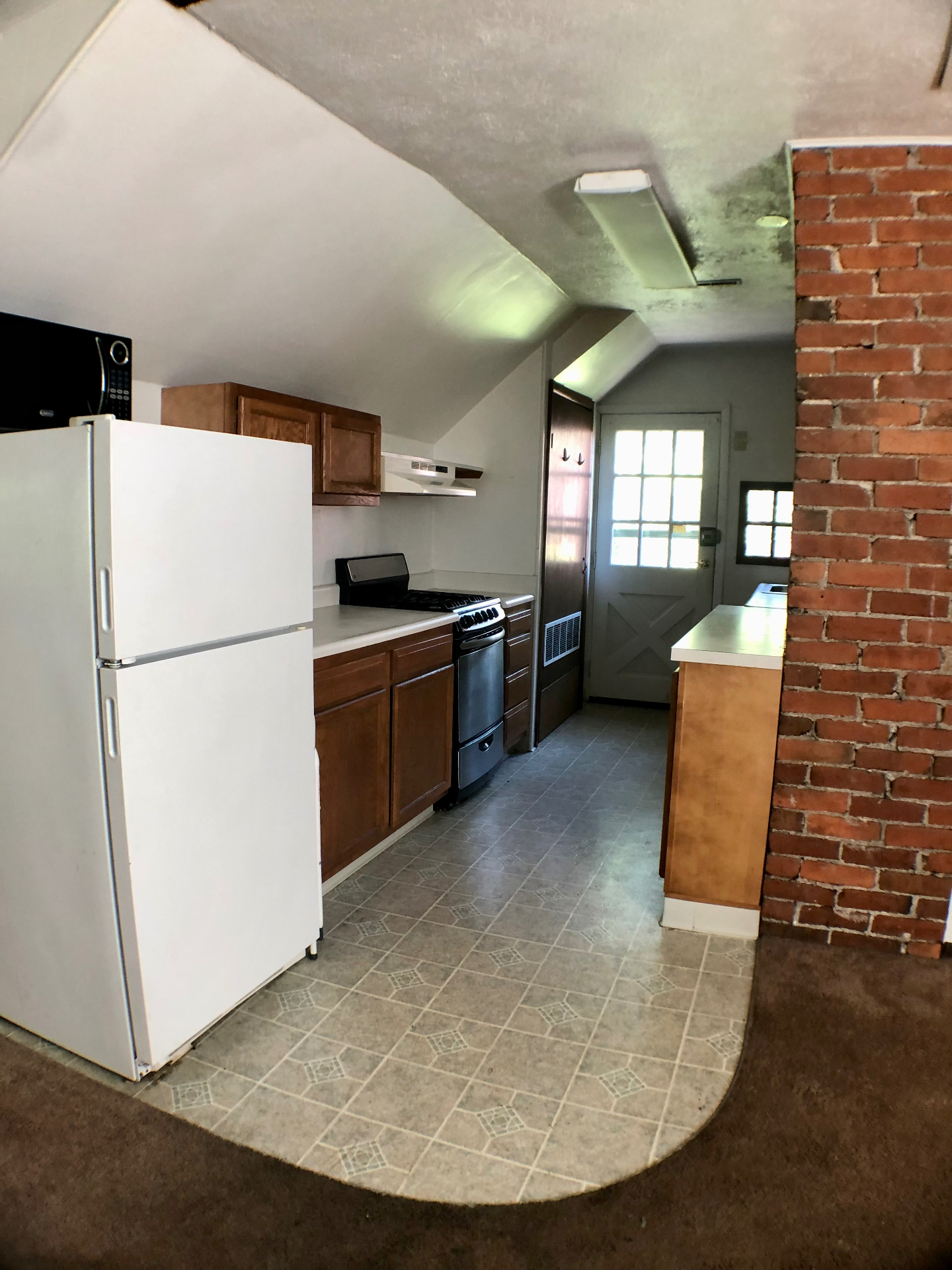 Galley kitchen with stainless gas range and exposed brick chimney