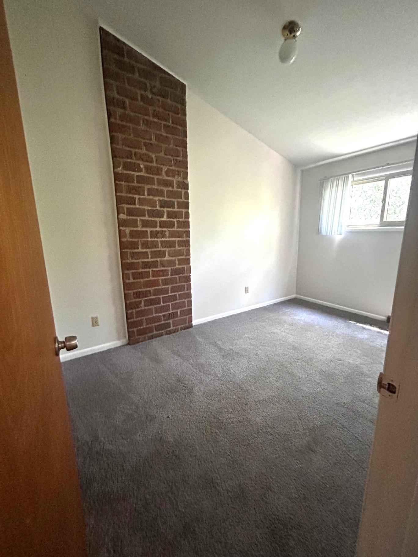 2011 Summit St. Unit E second bedroom with exposed brick accent wall and gray carpet