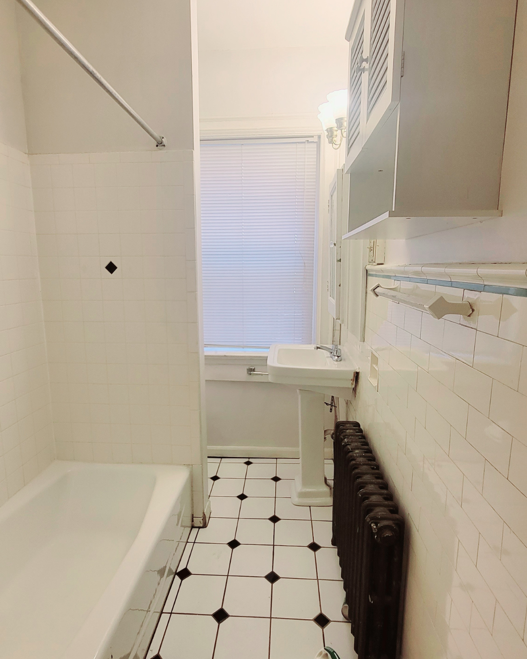 Unit A bathroom with pedestal sink, tub, radiator, and white tile floor