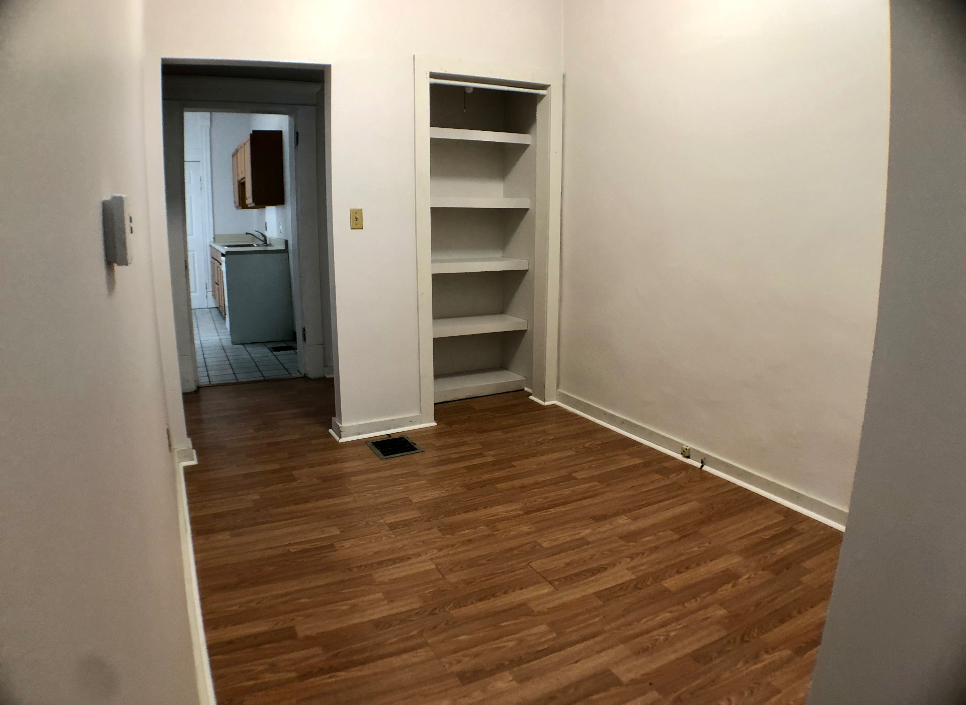 Unit A bedroom with built-in shelving closet and view into the kitchen