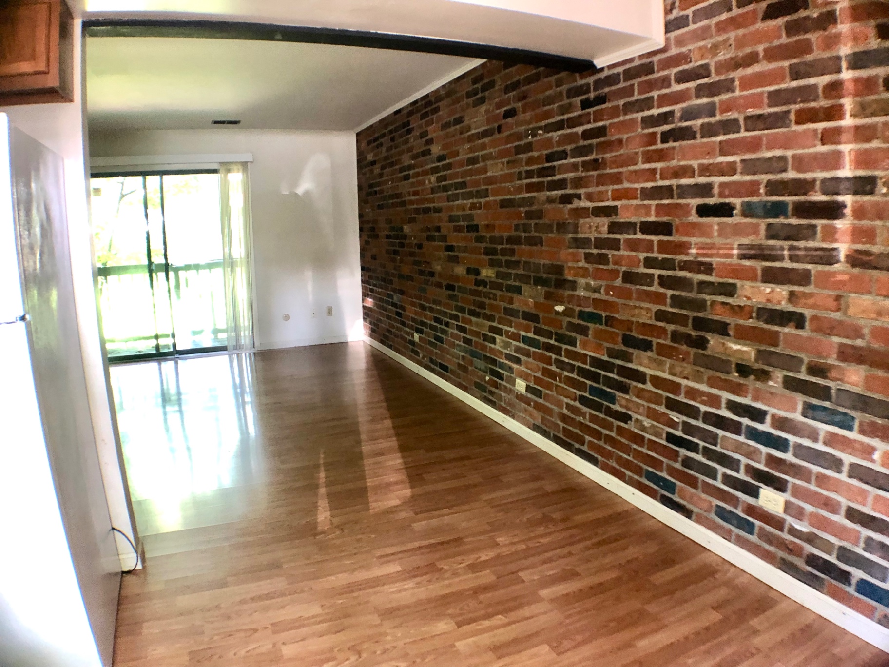 2018 Iuka Ave. open living and dining area with exposed brick wall and balcony access