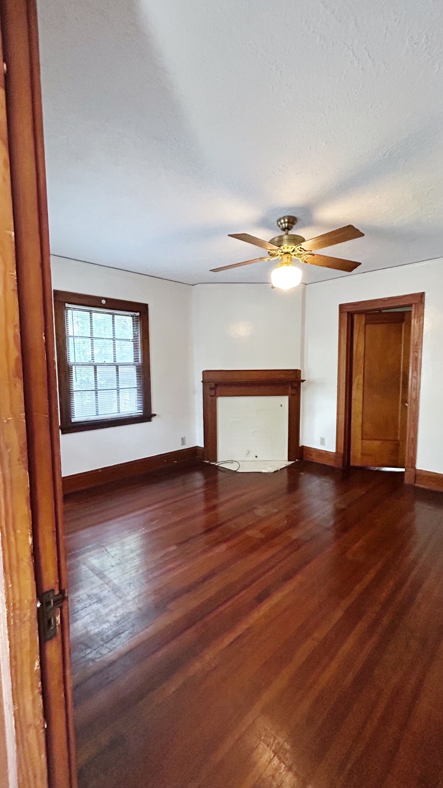 2026 Iuka Ave C bedroom with wood mantel fireplace, glossy hardwood floors, and ceiling fan