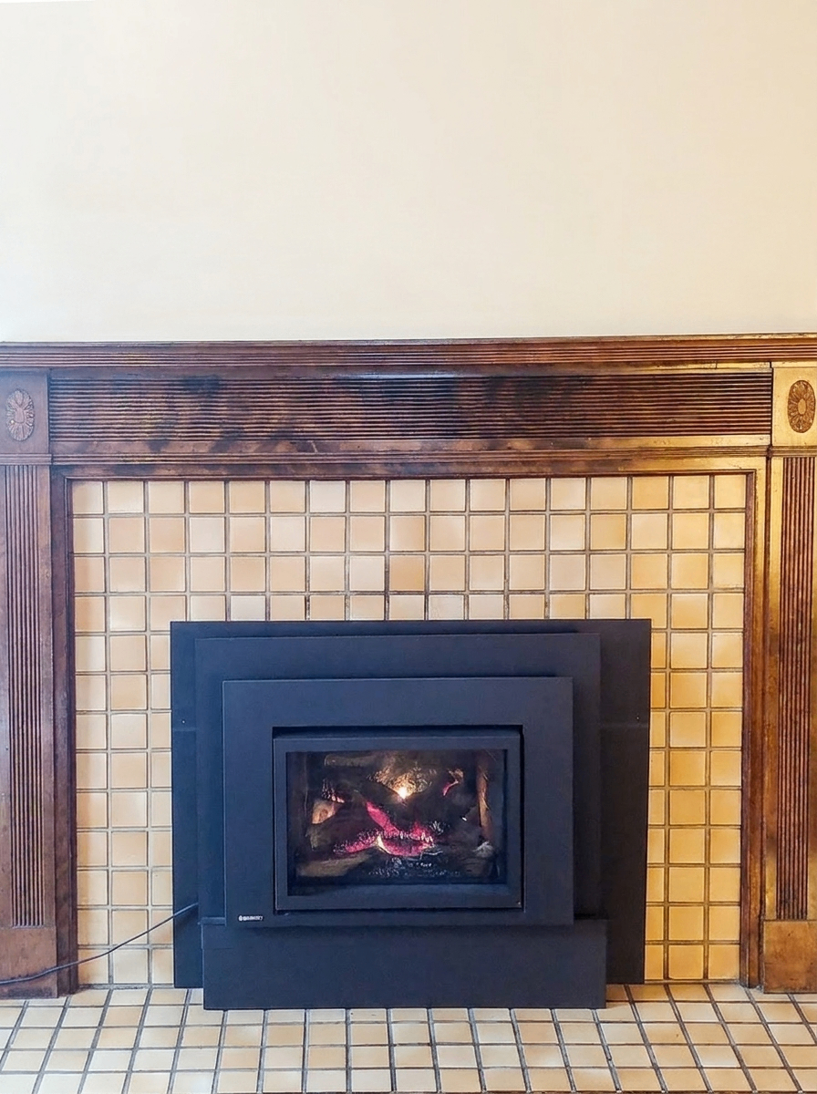 Close-up of Unit C gas insert fireplace with tile surround and wood mantel