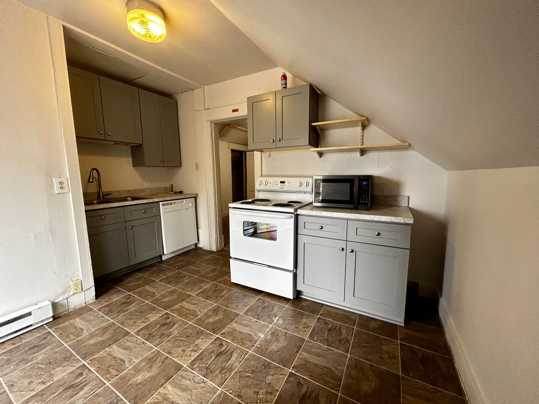 1820 Summit St. updated kitchen with gray shaker cabinets, white range, dishwasher, microwave, and tile floor