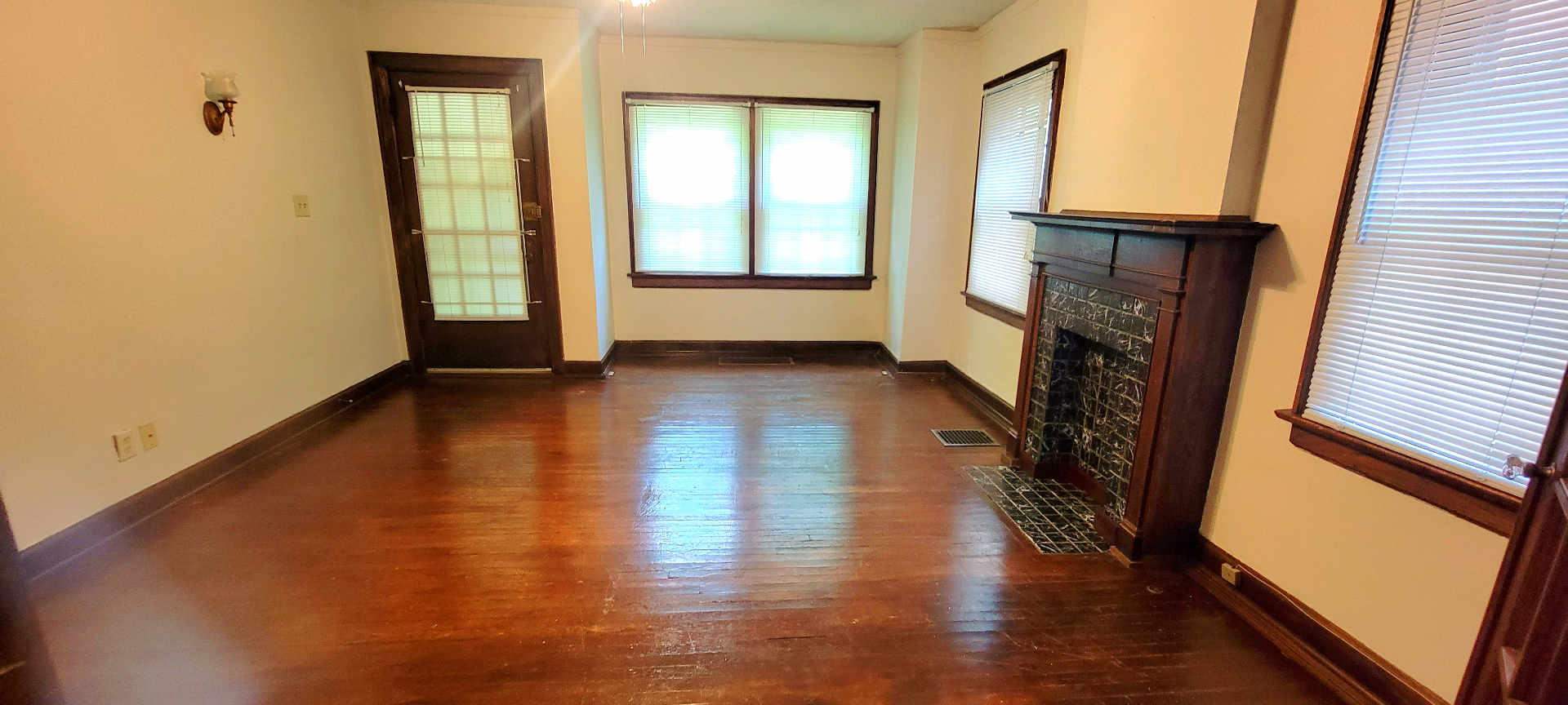 2048 Iuka Ave. A living room with decorative tile fireplace, hardwood floors, and bright front windows
