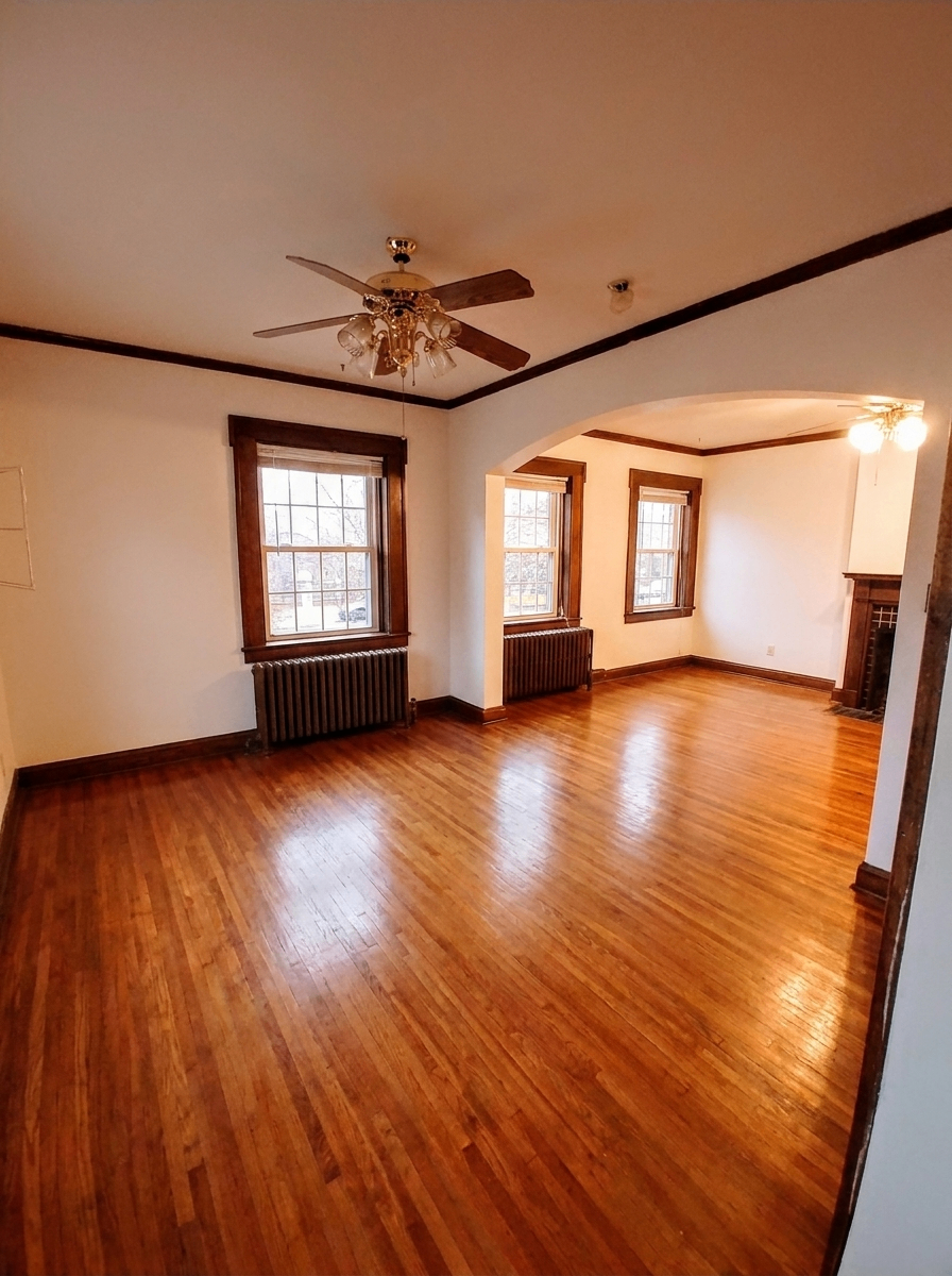 Unit B spacious living room with archway, radiators, and glossy hardwood floors
